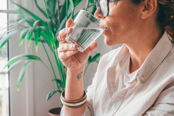 Γυναίκα πίνει από ένα ποτήρι νερό. Φωτογραφία έννοιας υγειονομικής περίθαλψης, τρόπος ζωής, κοντινό πλάνο  - Φωτογραφία, εικόνα