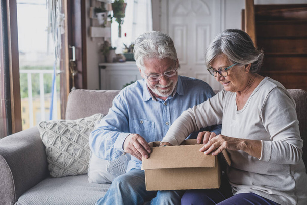 Happy mature aged older family couple unpacking carton box, satisfied with internet store purchase or unexpected gift, feeling excited of fast delivery shipping service, positive shopping experience.  - Фото, зображення