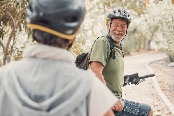 Kaksi onnellista vanhaa kypsää ihmistä nauttimassa ja pyöräilemässä yhdessä ollakseen kunnossa ja terveitä ulkona. Aktiivinen seniorit hauskaa koulutusta luonnossa. Muotokuva vanhasta miehestä hymyilemässä pyöräretkellä vaimonsa kanssa. Nainen osoittaa jotain ja katsoo sitä.. - Valokuva, kuva