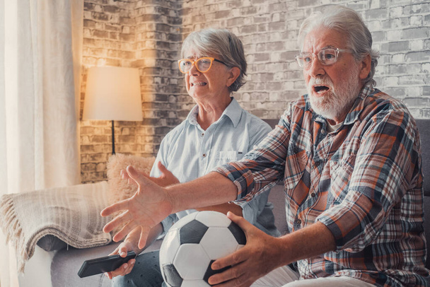Happy couple of seniors or football fans watching soccer on tv and frustrating and getting mad at home. Family, sports and entertainment concept.  - Foto, Imagen