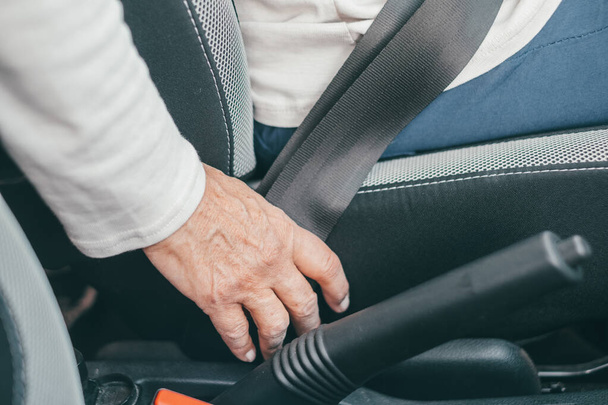 close up of one mature woman and putting on seat belt in a car to be safe and secure while driving with care - Foto, immagini