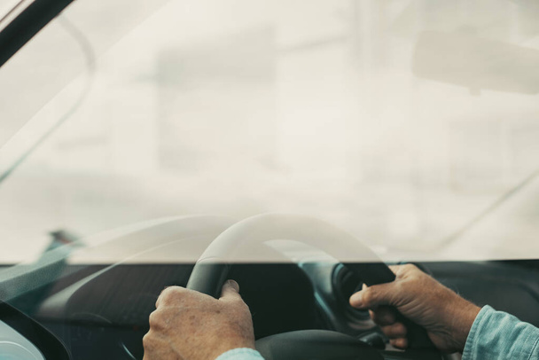 Close up and portrait of old and retired man holding steering wheel with his hands driving and enjoying new car in the road. Satisfied client concept - Φωτογραφία, εικόνα