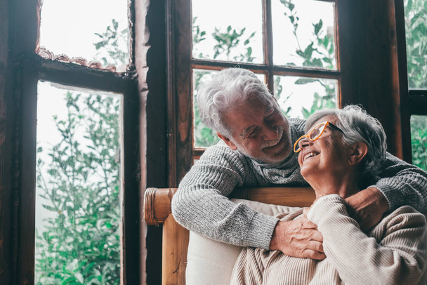 Portrait de deux personnes âgées heureuses et en bonne santé qui se sourient et se regardent. Gros plan de grands-parents matures appréciant et s'amusant ensemble à la maison intérieure.   - Photo, image