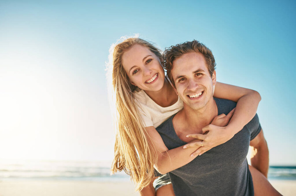 L'amour rend l'été encore plus génial. un jeune couple heureux profitant d'une balade à dos de cochon à la plage - Photo, image