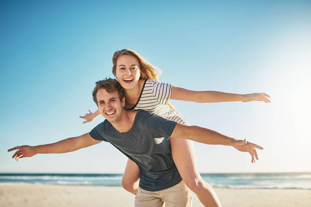 La liberté, c'est vivre une vie remplie d'amour. un jeune couple heureux profitant d'une balade à dos de cochon à la plage - Photo, image