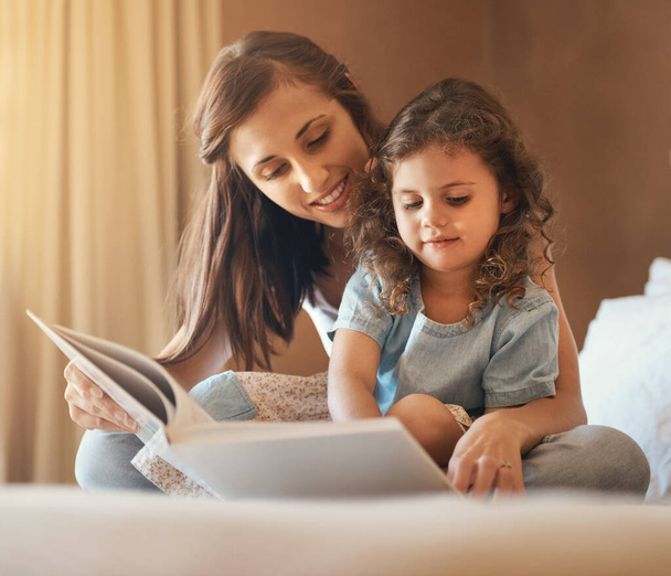 Können wir eines Tages in einem Schloss leben? eine glückliche Mutter und Tochter zu Hause beim Lesen eines Märchenbuchs auf dem Bett - Foto, Bild