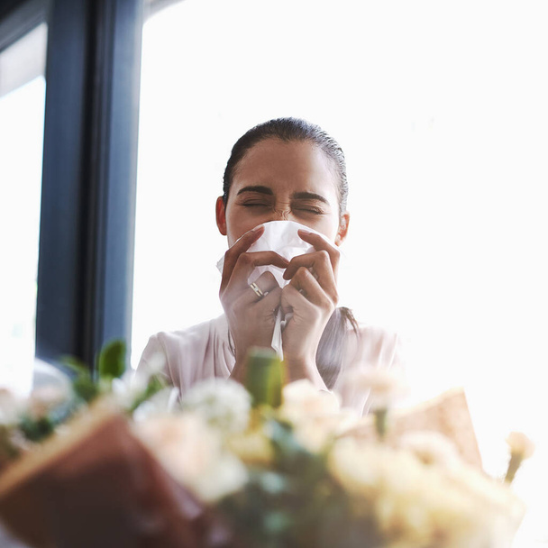 Das sind schöne... achoo. eine junge Geschäftsfrau bläst ihre Nase vor einem Blumenstrauß - Foto, Bild