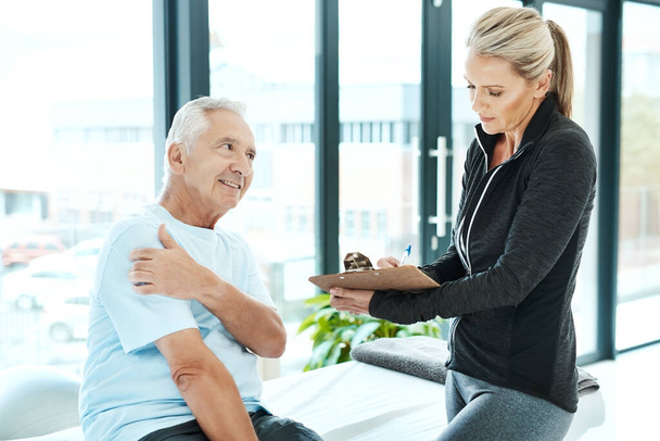 Wie lange haben Sie dieses Unbehagen schon gespürt. ein älterer Mann berät sich mit seiner Physiotherapeutin in ihrem Büro - Foto, Bild
