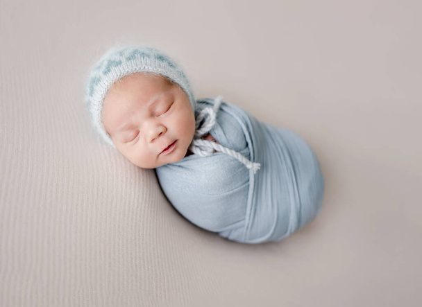 Newborn baby boy sleeping swaddled in fabric studio portrait. Infant child kid napping - Photo, Image