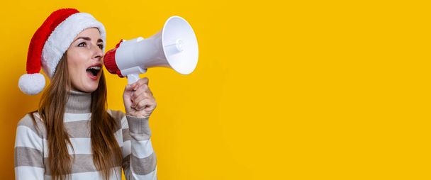 Young woman talking into a megaphone on a yellow background. Banner.  - Foto, afbeelding