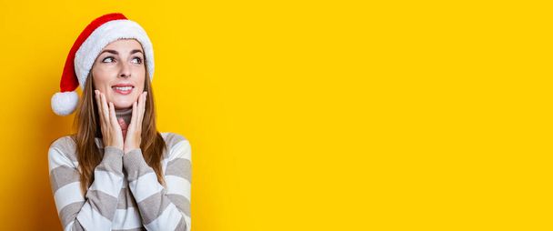 Mujer joven pensativa sosteniendo sus manos sobre su barbilla sobre un fondo amarillo. Banner.  - Foto, Imagen