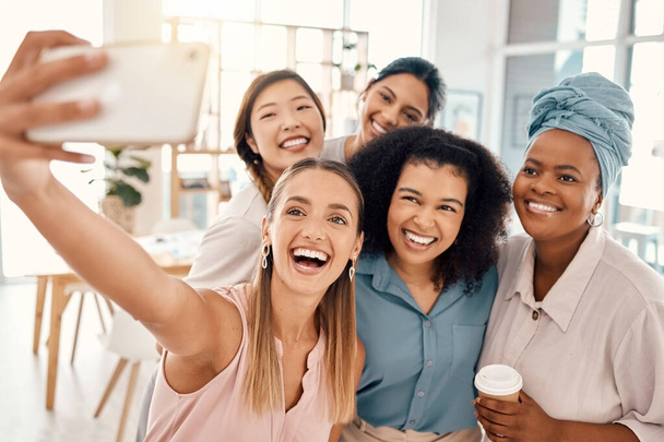 Irodai, fajok közötti és a nők telefon szelfi boldog mosollyal a sokszínűség, a barátok és a csapatépítés. Professzionális és változatos személyzet munkahelyi elfog fénykép okostelefonon a közösségi média - Fotó, kép