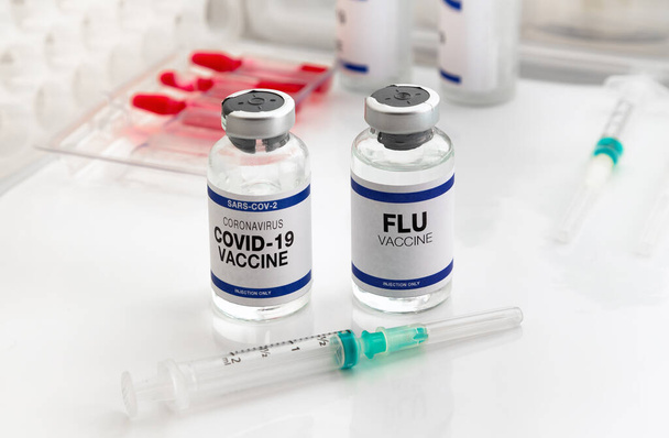 Εμβόλιο του Coronavirus και φιαλίδιο γρίπης για αναμνηστικό εμβολιασμό για νέες παραλλαγές του ιού Sars-cov-2 και της γρίπης A. Φύσιγγες εμβολίου γρίπης και Covid- 19 για αναμνηστική ένεση για τον ιό της γρίπης και το covid omicron - Φωτογραφία, εικόνα