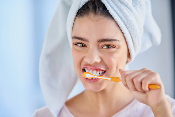 Oral hygiene is very important to me. Cropped portrait of a beautiful young woman brushing her teeth in the bathroom at home - Zdjęcie, obraz
