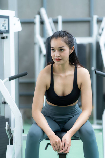 weight training Asian woman exercising in fitness gym, lifting weights, strong body, in sportswear, health care motivation concept, smiling at the gym. - Photo, image