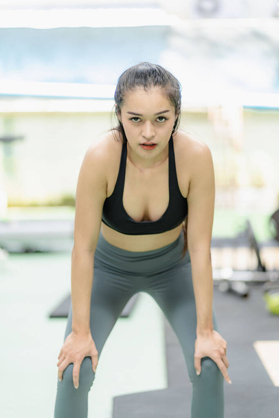 важке тренування Азіатська жінка займається фітнес-гімнастикою, піднімає тягарі, сильне тіло, спортивного одягу, мотивації до охорони здоров'я, посміхається в спортзалі. - Фото, зображення