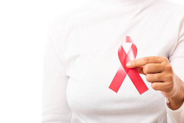 Female holding HIV AIDS awareness red ribbon on hands in studio shot isolated on over white background, Healthcare and medicine, World aids day concept - Fotó, kép