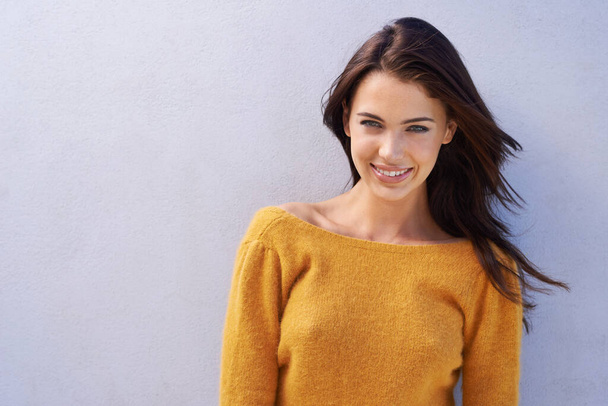 Větrné štěstí. Portrét krásné mladé ženy stojící u šedé zdi - Fotografie, Obrázek