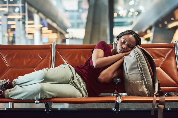 待ち時間はかなり長くなる可能性があります。出発を待つ間に空港で眠っていた若い女性が - 写真・画像