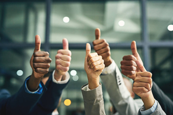 We couldnt agree more. Closeup shot of a group of unidentifiable businesspeople showing thumbs up in an office - Photo, Image