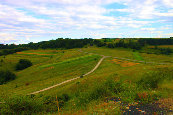 Kreuzung in ländlicher Landschaft auf dem Wiesenhügel. Metapher Lebenskreuzweg  - Foto, Bild
