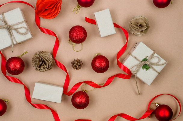 Christmas decorations concept. Top view gift boxes wrapping in craft paper, red baubles and ribbon on beige background. Xmas celebration, preparation for winter holidays.  - Фото, зображення