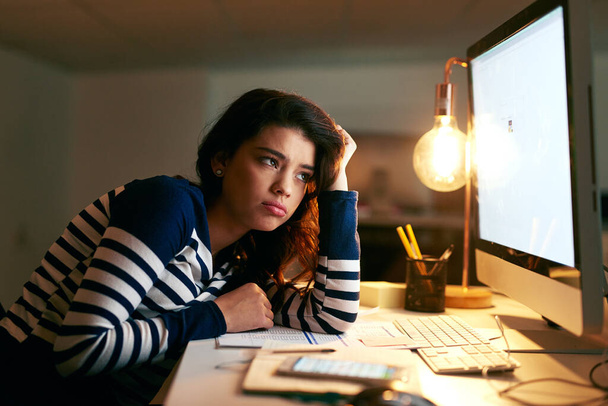 Its hard to stay motivated through the long hours. a young businesswoman looking bored while working late in an office - 写真・画像