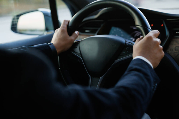 Man driving with his two hands on steering wheel. Business man driving in his modern electric car. Caucasian businessman driving himself to work. - Foto, Imagen