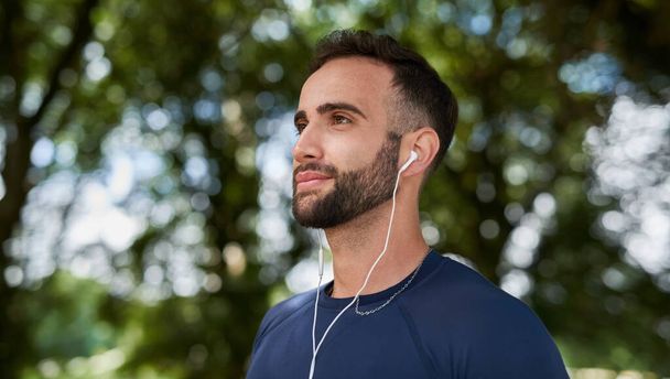 His eyes are focused on the finish. a handsome young male runner listening to music during his workout - Photo, Image