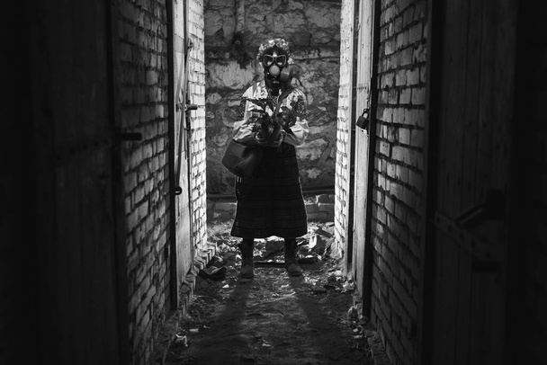 Oekraïense vrouw met een gasmasker, een pot met een plant. Gekleed in een traditioneel volkskostuum. Ze verstoppen zich in de schuilkelders voor chemische, radioactieve aanvallen, met giftige gassen, straling. - Foto, afbeelding