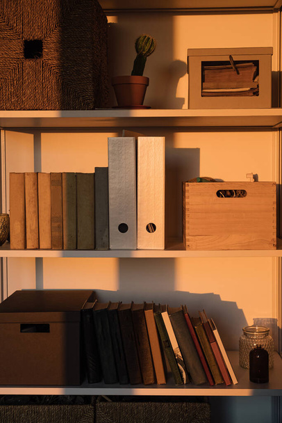 Sunlight shadow on storage shelves with books, boxes. Aesthetic home office interior design - Photo, Image