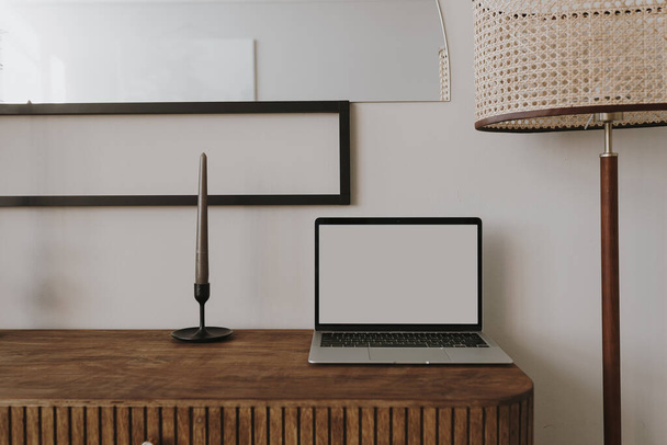 Laptop computer on wooden console with candle, floor lamp. Aesthetic elegant styled home living room interior design. Online store, blog, social media, shop branding template with blank copy space - Photo, Image