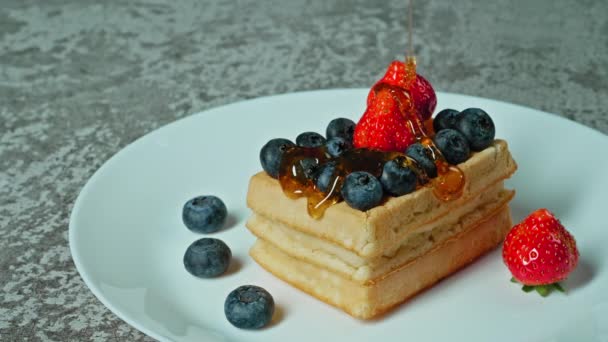 Belgialaisia vohveleita aamiaiseksi hunajan ja marjojen kanssa, konsepti aamiaisen myymiseksi hunajamarjoja. Laadukas 4k kuvamateriaalia - Materiaali, video