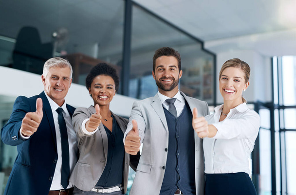 Ευτυχισμένοι συνάδελφοι σημαίνει μια ευτυχισμένη επιχείρηση. μια δυναμική επιχειρηματική ομάδα που δείχνει τους αντίχειρες και χαμογελά - Φωτογραφία, εικόνα
