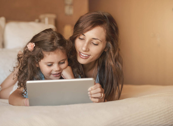 Leren en plezier hebben. een gelukkig moeder en dochter hebben plezier thuis tijdens het spelen op een tablet - Foto, afbeelding