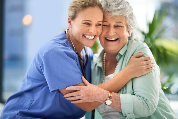Ze hebben nogal een band gevormd. een aantrekkelijke vrouwelijke verpleegster en haar senior patiënt in het ziekenhuis - Foto, afbeelding