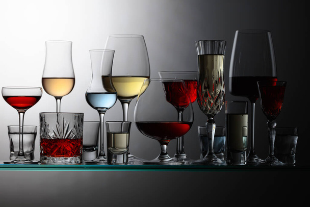 Various alcoholic drinks in the bar on glass shelves. - Zdjęcie, obraz