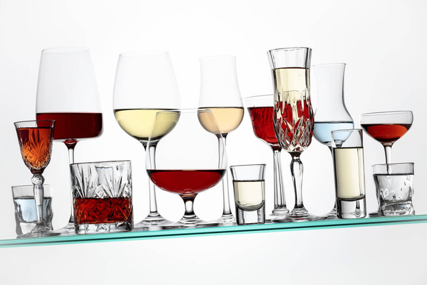 Various alcoholic drinks in a bar on a tilted glass shelf. - Zdjęcie, obraz
