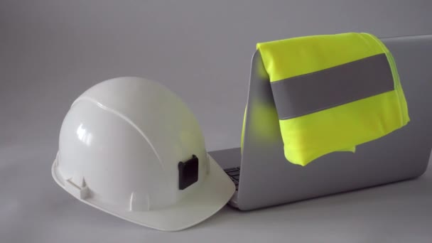 Koncept stavebnictví, designu, architektury nebo stavebnictví na pracovišti. Bílá bezpečnostní helma hardhat, reflexní vesta a notebook na stole inženýrů. Vysoce kvalitní 4k video záběry - Záběry, video