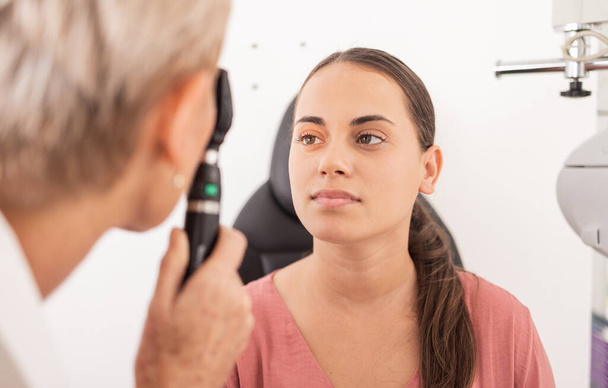 Oční vyšetření zraku, pacient nebo žena s optometristou na test glaukomu, oční podporu nebo lékařskou konzultaci. Oční péče, zrak nebo oftalmologie expert s oftalmoskopem pro kontrolu sítnice. - Fotografie, Obrázek