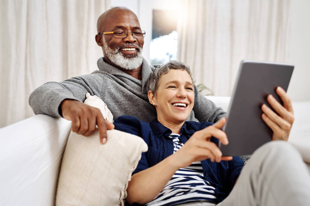 Manapság ez a legjobb módja, hogy eltöltsük a napjainkat. egy szerető idős pár, akik tablettát használnak, miközben otthon pihennek a kanapén. - Fotó, kép