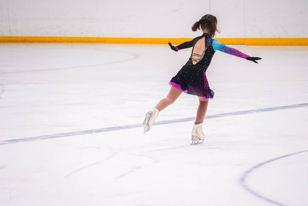 Küçük kız buz pateni pistinde artistik buz pateni yarışmasından önce pratik yapıyor.. - Fotoğraf, Görsel