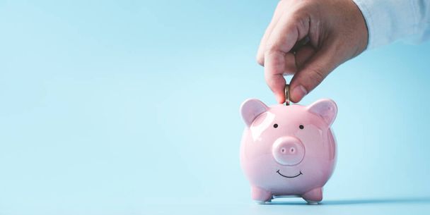Geschäftsmann Hand legt Münze auf rosa Sparschwein mit Kopierraum für Einlagen Banking von Investitionen, Ruhestand, um Gewinn und Zinskonzept zu erhalten. - Foto, Bild