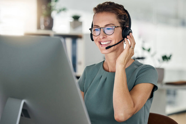Happy, call center and computer, woman and headphones at desk, customer support or sales for telemarketing company. Mature agent or consultant, office and working, communication and customer service. - Photo, Image