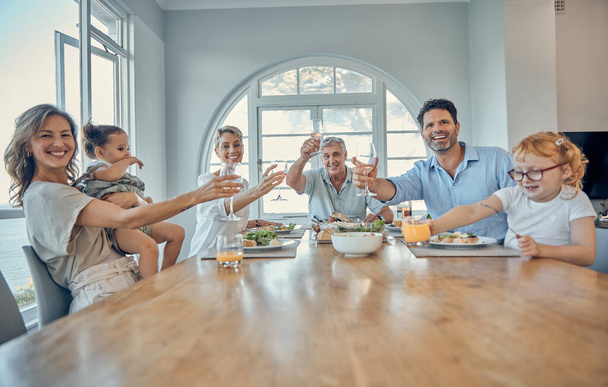 Család, vacsora étel és éljenzés egy anya, idősek és gyerekek boldog otthon. Egy boldog pohárköszöntő portréja, anya és apa gyerekekkel egy asztalnál, akik egy boldog házban esznek.. - Fotó, kép