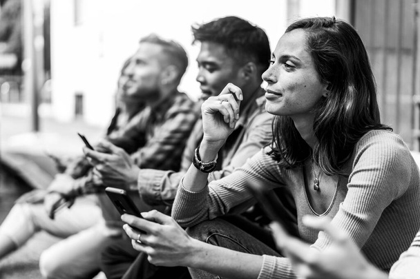 Pensive ystävien ryhmä, joka käyttää älypuhelinta istuu yliopiston takapihalla - Nuoret riippuvaisiksi mobiili älypuhelin - Teknologia surullinen elämä käsite aina kytketty opiskelijat - Retro editointi - Valokuva, kuva
