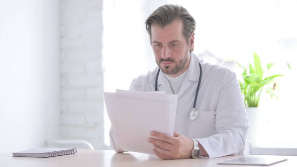 Male Doctor Doing Paperwork in Clinic - Photo, Image