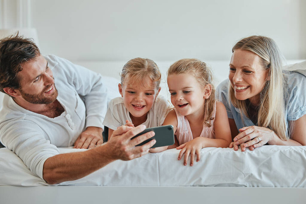 Famille, chambre et selfie pour coller et aimer à la maison avec un smartphone. Lit, téléphone et photo de parents heureux se détendre ensemble pour l'affection, l'amour et la relation bienveillante à la maison. - Photo, image