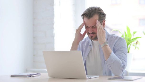 Ώριμος άνθρωπος που έχει πονοκέφαλο ενώ εργάζεται σε φορητό υπολογιστή - Φωτογραφία, εικόνα