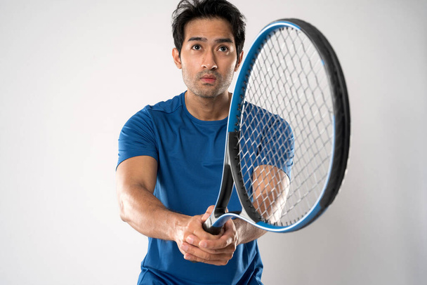 白地に決定的な表情と目を持つテニスラケットを持つ男子テニス選手. - 写真・画像